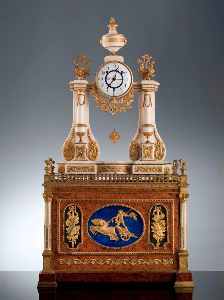 Reloj de sobremesa francés. Autor del mecanismo: Meuron y Compañía, h. 1790-1800, mármol blanco, bronce dorado y bronce cincelado (reloj); madera de olivo, estaño, latón, bronce cincelado, repujado y dorado, Florencia, Galería de los Uffizi, Galería Palatina y Apartamentos Reales, Salón de la Caridad